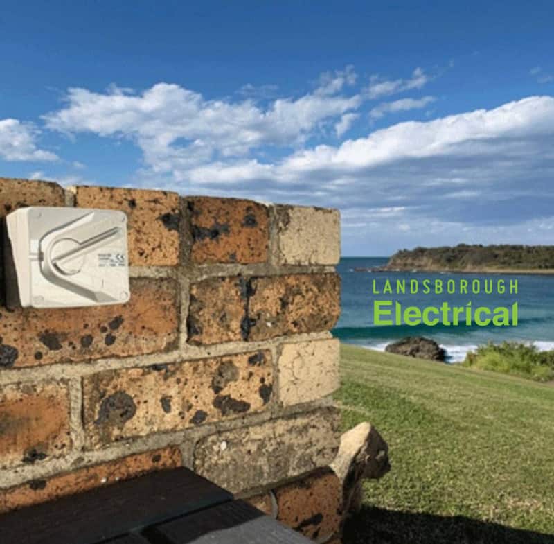 Outdoor electrical power outlet on a brick wall on a coastal headland with Landsborough Electrical sign